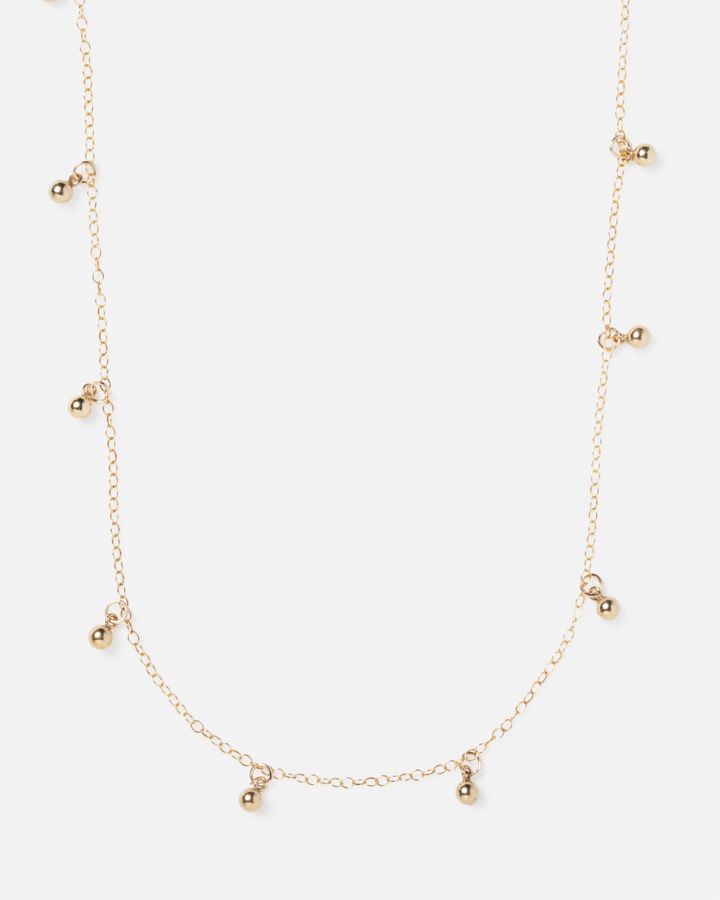 small gold ball charms hanging off of gold necklace