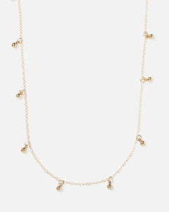 small gold ball charms hanging off of gold necklace